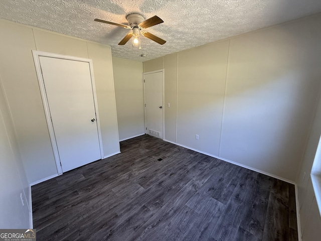 unfurnished bedroom with ceiling fan, a textured ceiling, visible vents, a closet, and dark wood-style floors