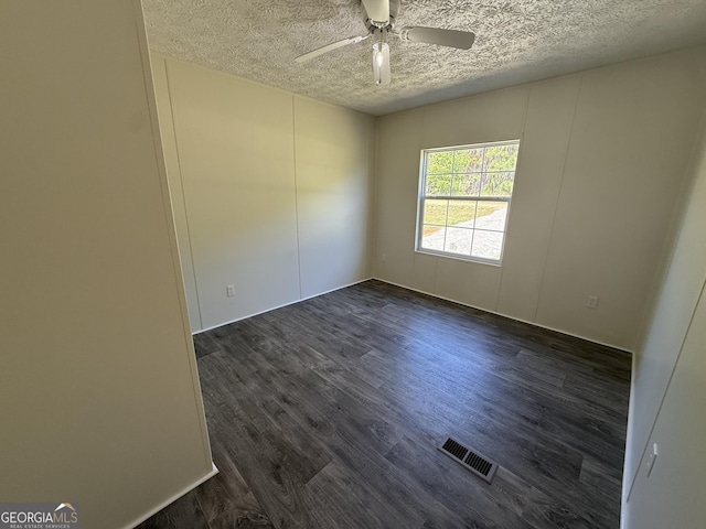 empty room featuring visible vents, a textured ceiling, ceiling fan, and dark wood finished floors