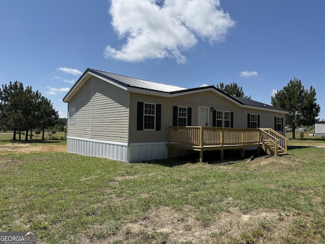 back of property with a wooden deck, a yard, and metal roof