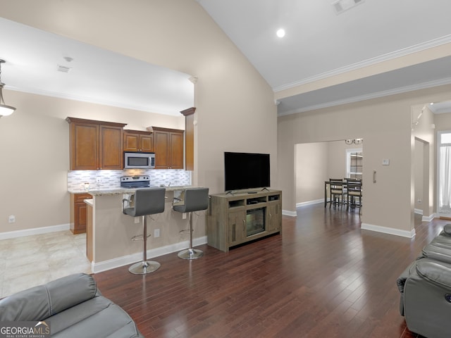 living room featuring dark wood-style floors, high vaulted ceiling, visible vents, and ornamental molding