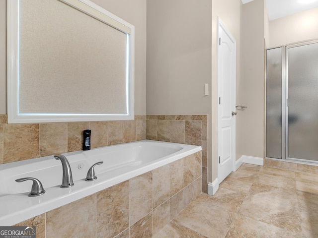 bathroom with baseboards, a shower stall, and a garden tub