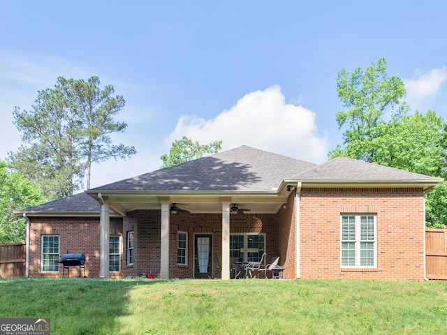 rear view of house with fence, a ceiling fan, and brick siding