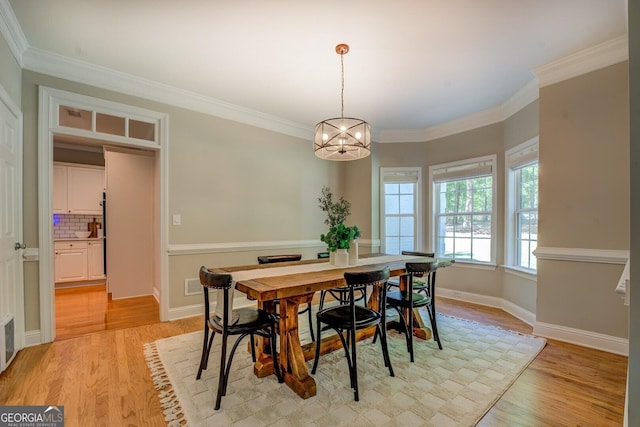 dining area with light wood-style floors, a chandelier, crown molding, and baseboards