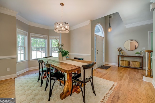 dining space with a chandelier, light wood finished floors, ornamental molding, and baseboards