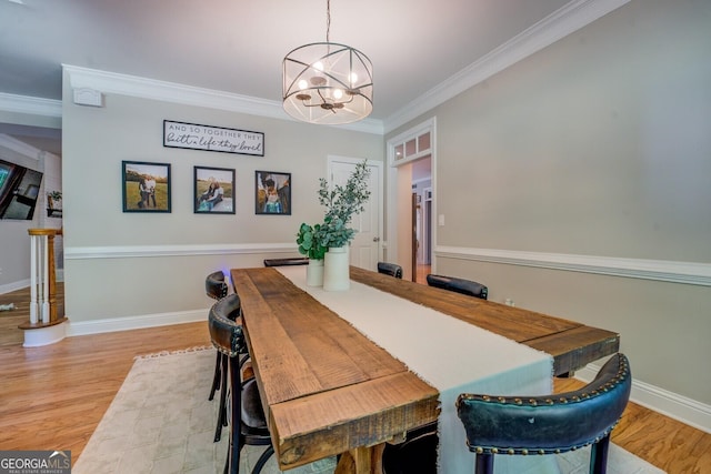 dining area featuring a chandelier, ornamental molding, light wood-type flooring, and baseboards