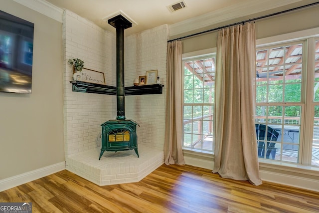 entryway featuring a wood stove, wood finished floors, ornamental molding, and baseboards