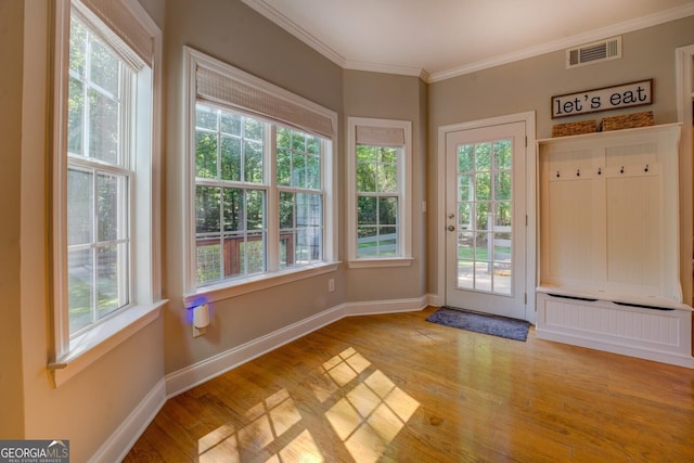doorway with plenty of natural light, light wood-type flooring, crown molding, and baseboards