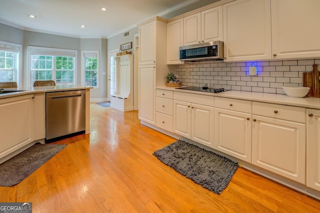857 Cooper Rd, Social Circle, GA 30025 - kitchen with stainless steel appliances, crown molding, decorative backsplash, white cabinetry, and light wood-style flooring