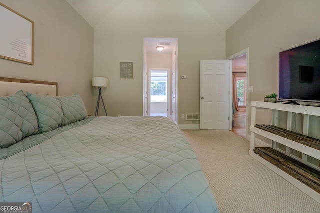 bedroom featuring vaulted ceiling, multiple windows, light carpet, and baseboards