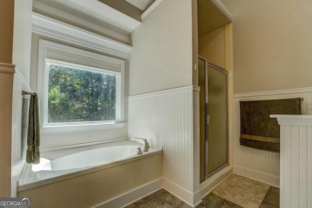 full bathroom with a shower stall, a wainscoted wall, and a bath