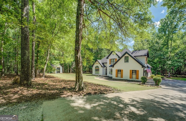 view of front of home featuring driveway, a storage unit, stucco siding, and an outbuilding