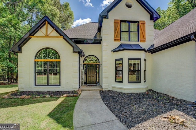 view of front of property with roof with shingles, a front yard, and brick siding