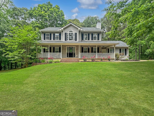 colonial-style house featuring covered porch, a chimney, and a front yard