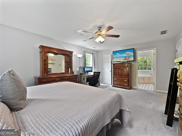 carpeted bedroom featuring ensuite bath, a textured ceiling, a ceiling fan, baseboards, and visible vents