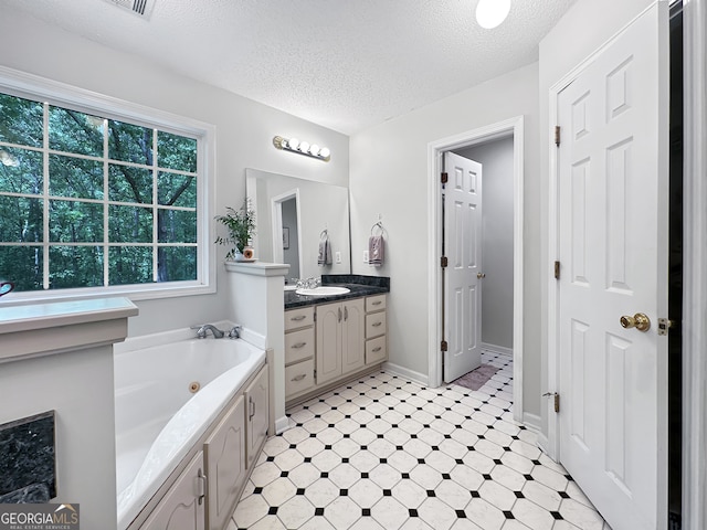 full bath featuring vanity, a textured ceiling, tile patterned floors, baseboards, and a tub with jets