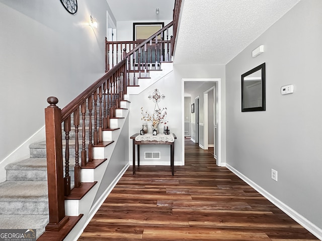 stairway with visible vents, baseboards, and wood finished floors