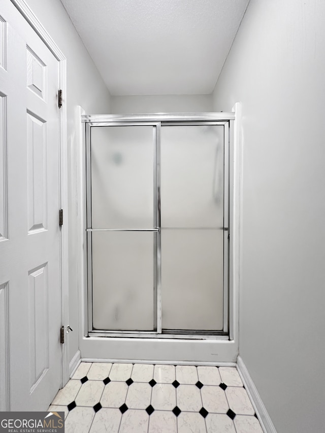 bathroom featuring tile patterned floors, baseboards, and a shower with door