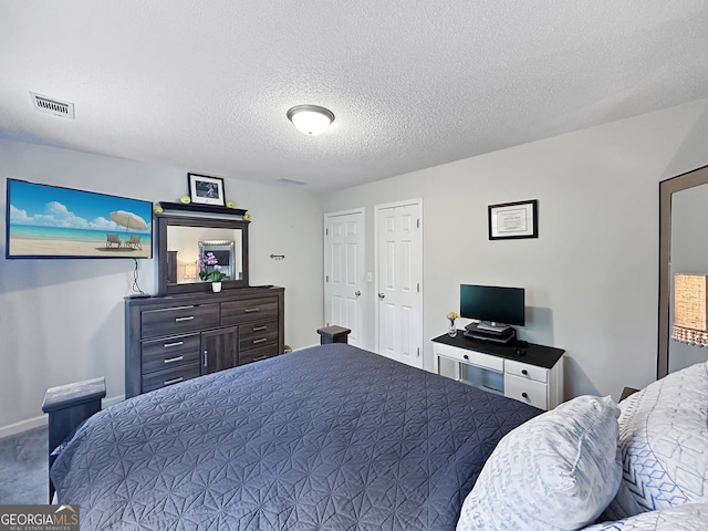 bedroom featuring carpet floors, baseboards, a textured ceiling, and visible vents