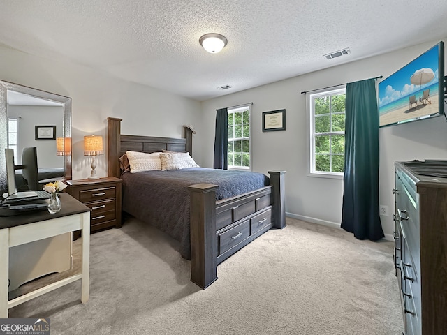 bedroom with light colored carpet, a textured ceiling, visible vents, and baseboards