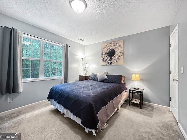 carpeted bedroom featuring a textured ceiling, visible vents, and baseboards