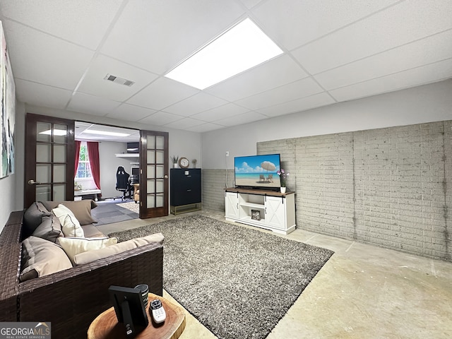 living room featuring visible vents, a paneled ceiling, and concrete floors