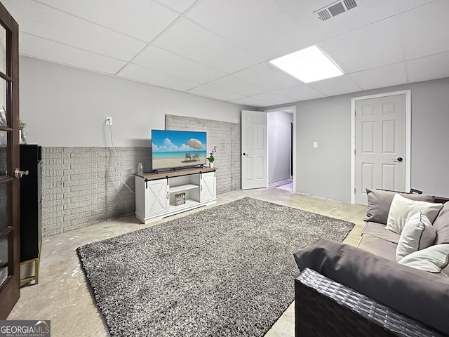 living room with concrete flooring, a drop ceiling, and visible vents