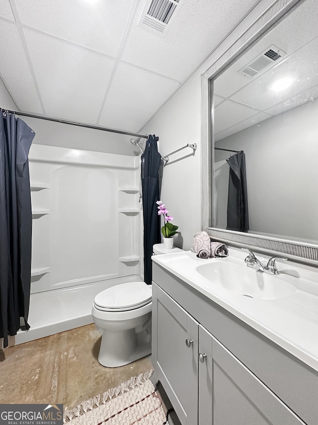 bathroom with a drop ceiling, toilet, curtained shower, and visible vents