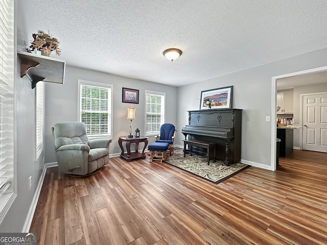 living area with a textured ceiling, baseboards, and wood finished floors