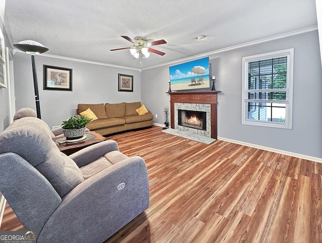 living area with crown molding, a ceiling fan, wood finished floors, and a premium fireplace