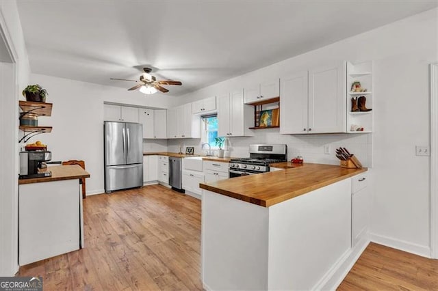 143 Navajo Trl, Rydal, GA 30171 - kitchen with appliances with stainless steel finishes, open shelves, a sink, a peninsula, and light wood-type flooring