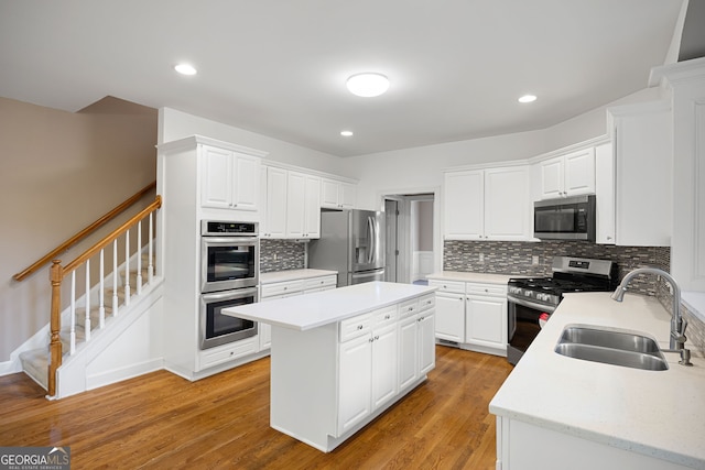 kitchen featuring a kitchen island, light countertops, tasteful backsplash, a sink, and stainless steel appliances