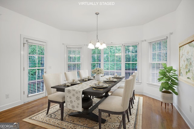 dining space with baseboards, an inviting chandelier, and wood finished floors