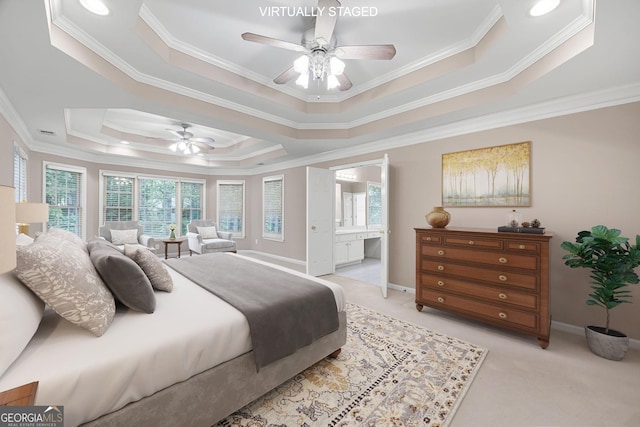 bedroom with crown molding, a tray ceiling, and connected bathroom
