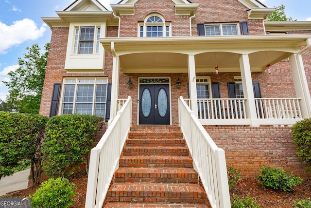 entrance to property with a porch and brick siding