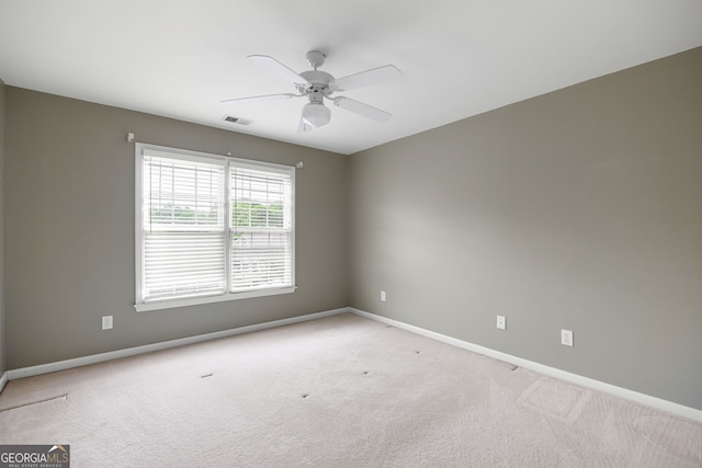 carpeted empty room with baseboards, visible vents, and ceiling fan