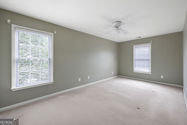 empty room with baseboards, light carpet, a ceiling fan, and visible vents