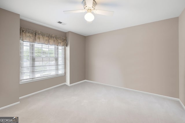 carpeted empty room with visible vents, a ceiling fan, and baseboards