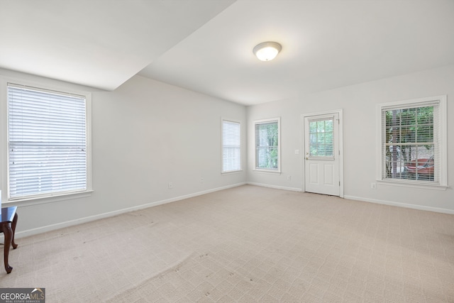 empty room featuring baseboards and light carpet