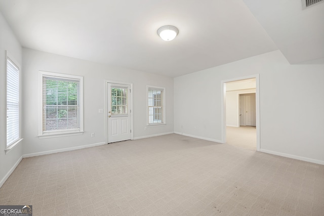 unfurnished living room with baseboards, light carpet, and visible vents