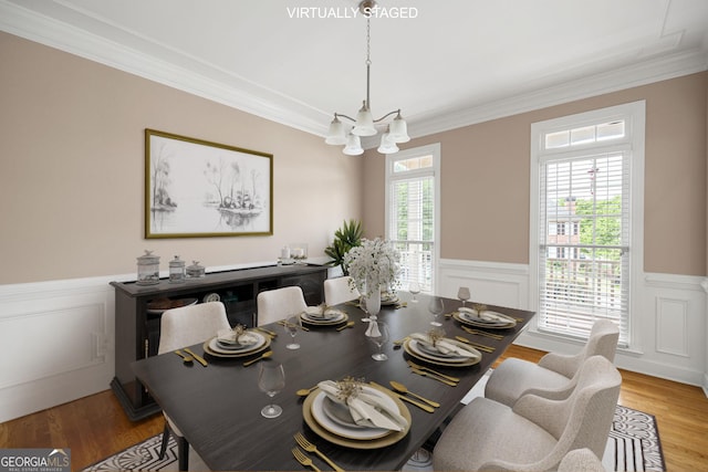 dining space with crown molding, a wainscoted wall, and an inviting chandelier