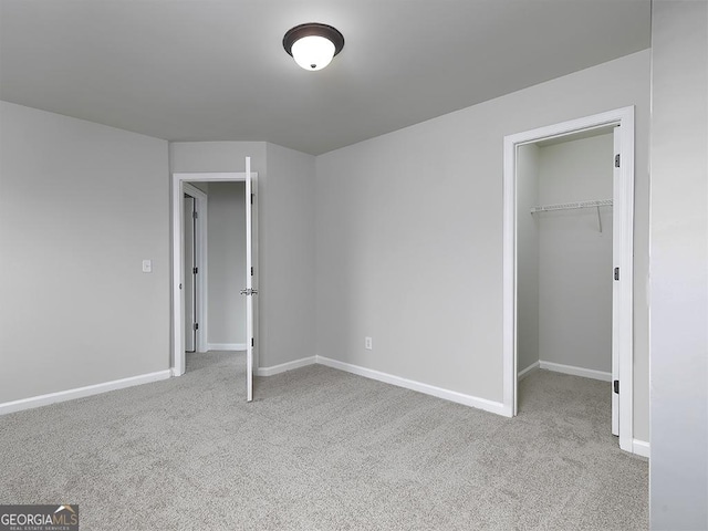 unfurnished bedroom with carpet floors, baseboards, a closet, and a walk in closet
