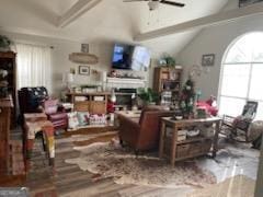 living area with ceiling fan, a fireplace, and lofted ceiling