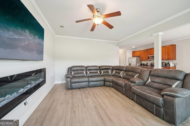 living area featuring light wood-style floors, baseboards, crown molding, and a ceiling fan