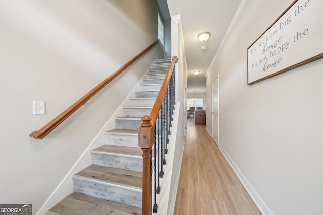 stairway with baseboards, ornamental molding, and wood finished floors