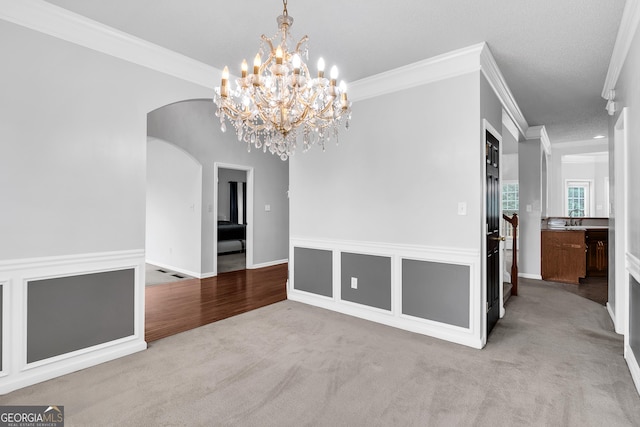 unfurnished dining area featuring carpet floors, ornamental molding, and arched walkways