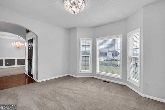 empty room with an inviting chandelier, carpet, and a healthy amount of sunlight