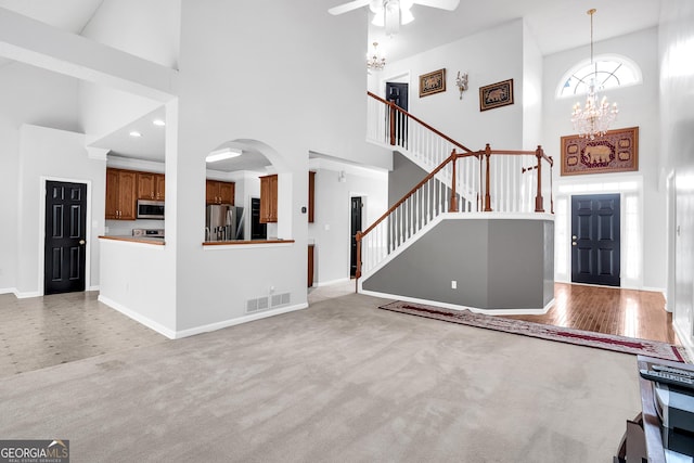 entryway with visible vents, baseboards, ceiling fan with notable chandelier, and a high ceiling