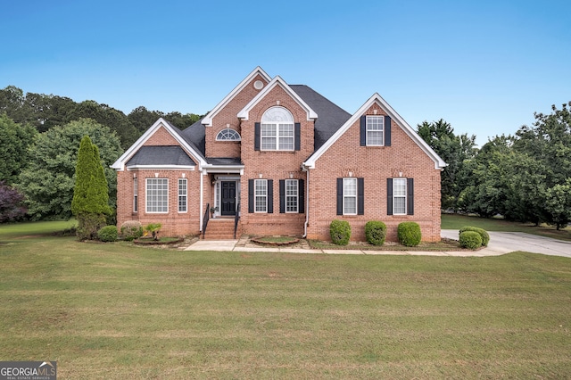 traditional-style home with brick siding and a front lawn