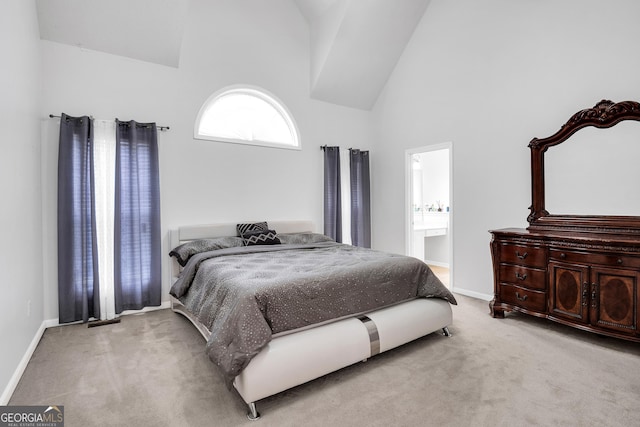 carpeted bedroom with ensuite bath, high vaulted ceiling, and baseboards