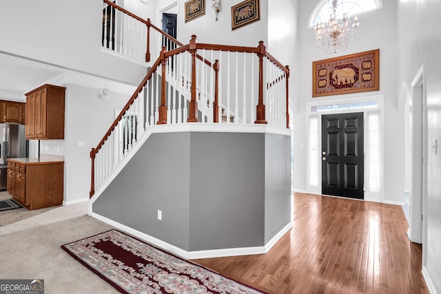 entryway with baseboards, stairway, an inviting chandelier, and a towering ceiling